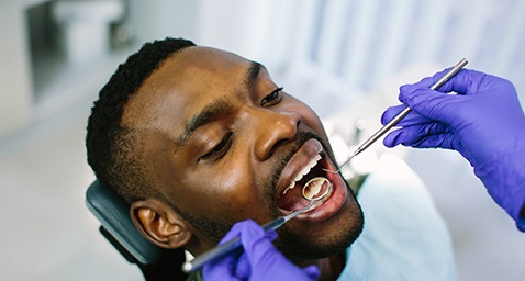 Dentist with blue gloves examining patient's teeth