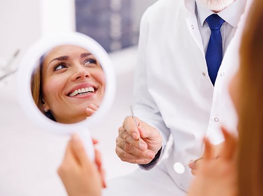 Woman smiling while holding handheld mirror